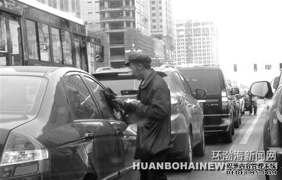在建設(shè)路新華道路口“擦車(chē)”的行乞者。田菲菲攝