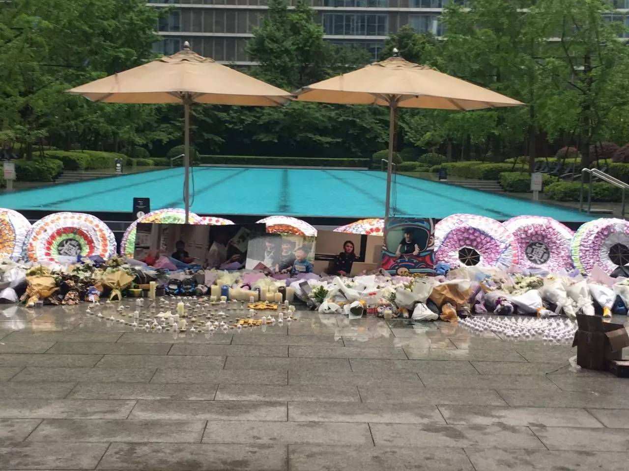 火災(zāi)后，小區(qū)業(yè)主自發(fā)組織悼唁活動，草坪上逝者照片前擺滿了花圈、花束、蠟燭。（新京報記者王婧祎攝）